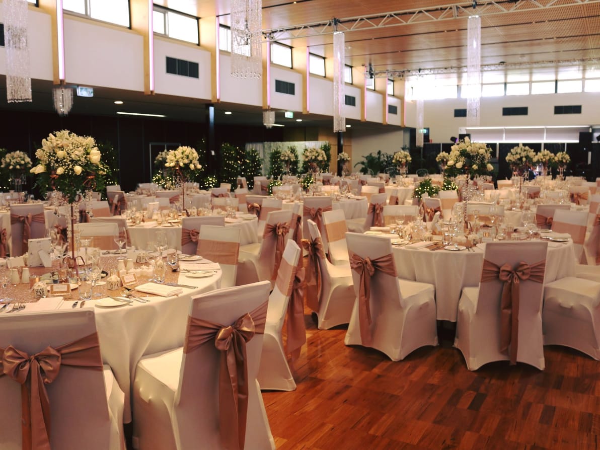 A large room filled with beautifully decorated round table with flowers