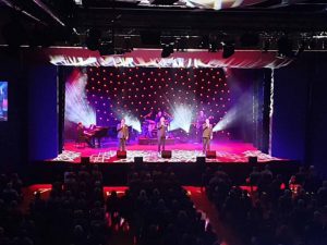 A group of singers and musicians singing and playing on stage